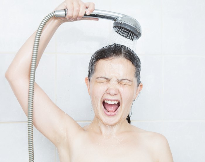 Portrait of a young woman in bathroom screaming in shower